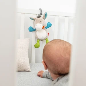 Otrok opazuje plišasto glasbeno igračo oslička na posteljici